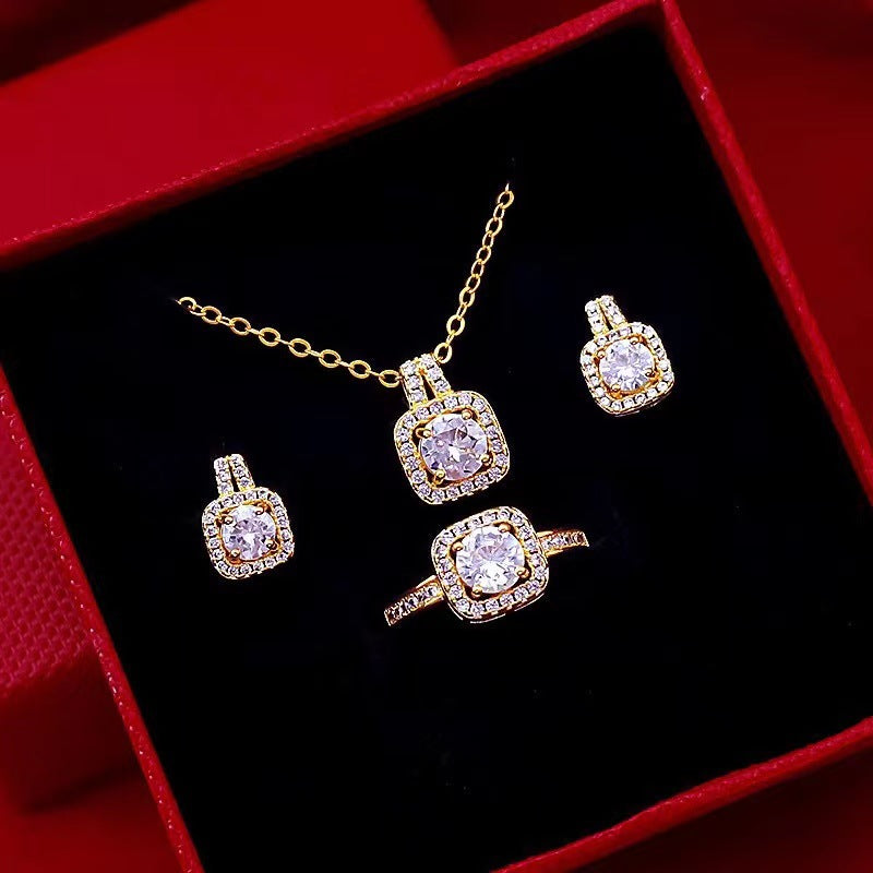 Gold zircon jewelry set with square pendant choker, matching studs, and ring on display