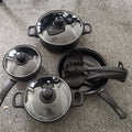 Black nonstick cookware set with three covered pots and two saucepans