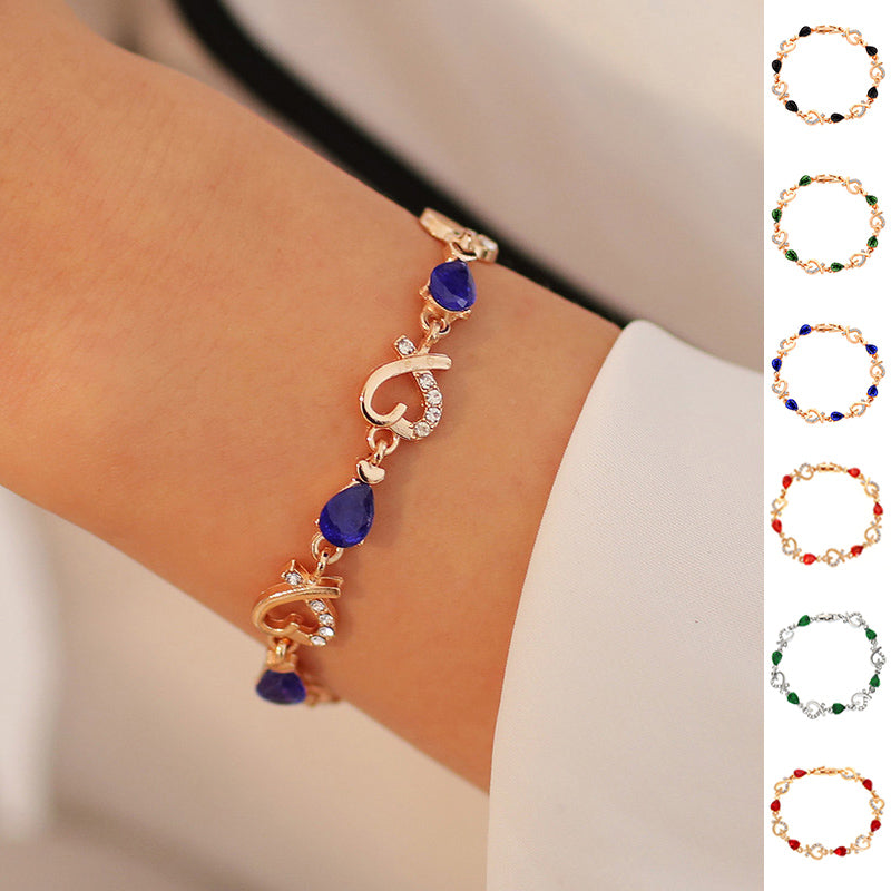 Rose gold heart charm bracelet with blue teardrop stones and clear rhinestones.