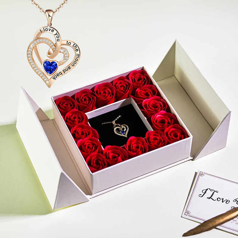Open jewelry box gift set with red roses and heart necklace pendant with blue crystal