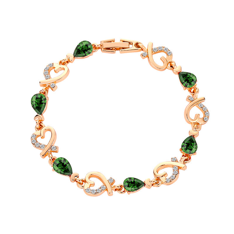 Rose gold heart bracelet with green teardrop stones and clear rhinestone heart charms.