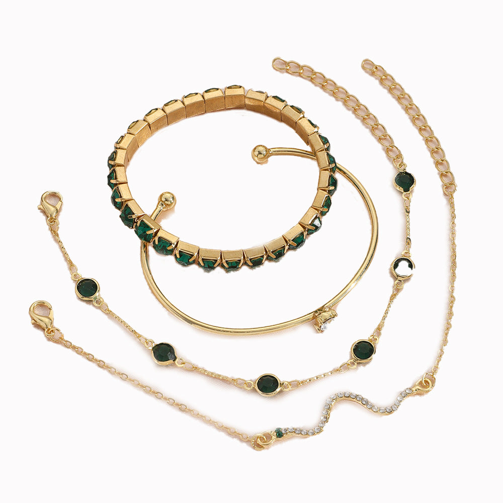 Gold-tone multi-bracelet set with green stone cuffs and linked chain bracelets, flat lay