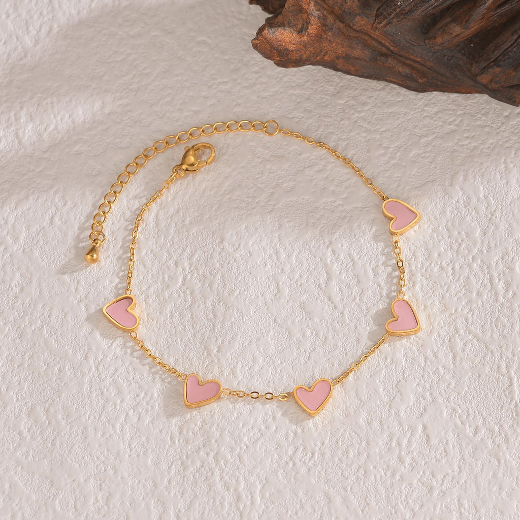 Gold-tone heart charm bracelet with light pink enamel heart links and clasp