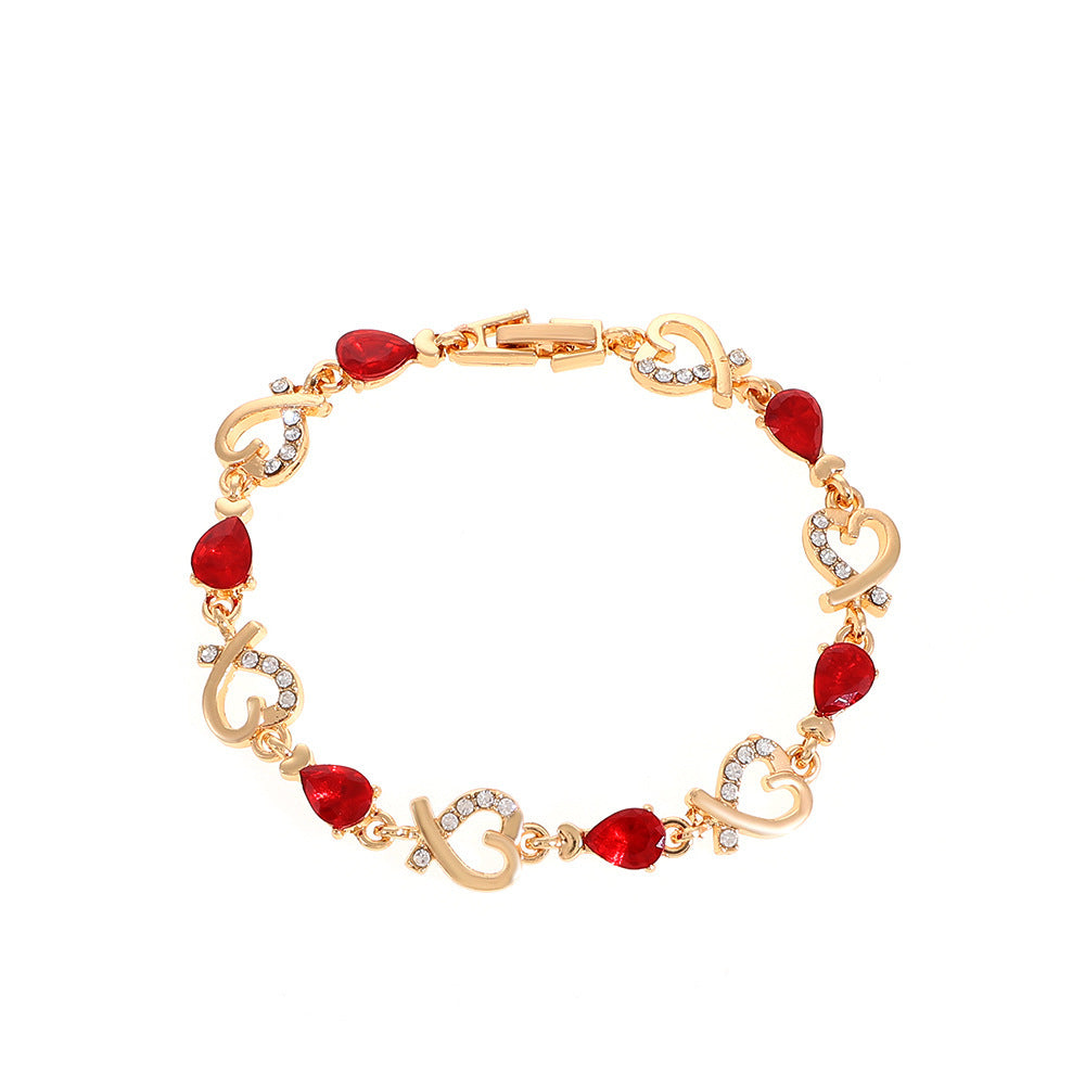 Rose gold heart bracelet with red teardrop stones and clear rhinestone heart details.