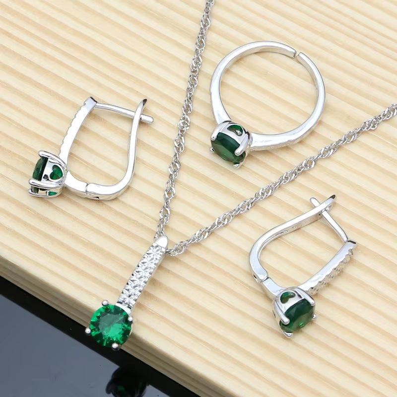 Sterling silver jewelry set with green gemstones: hoop ring, stud earrings, and pendant necklace