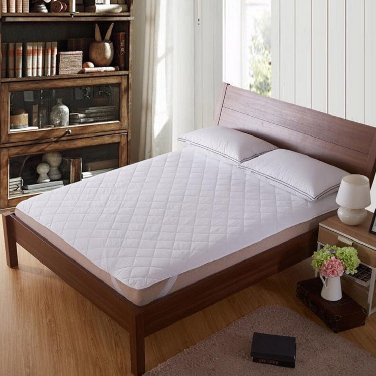 White quilted mattress topper on a bed with a visible top layer and fitted edge