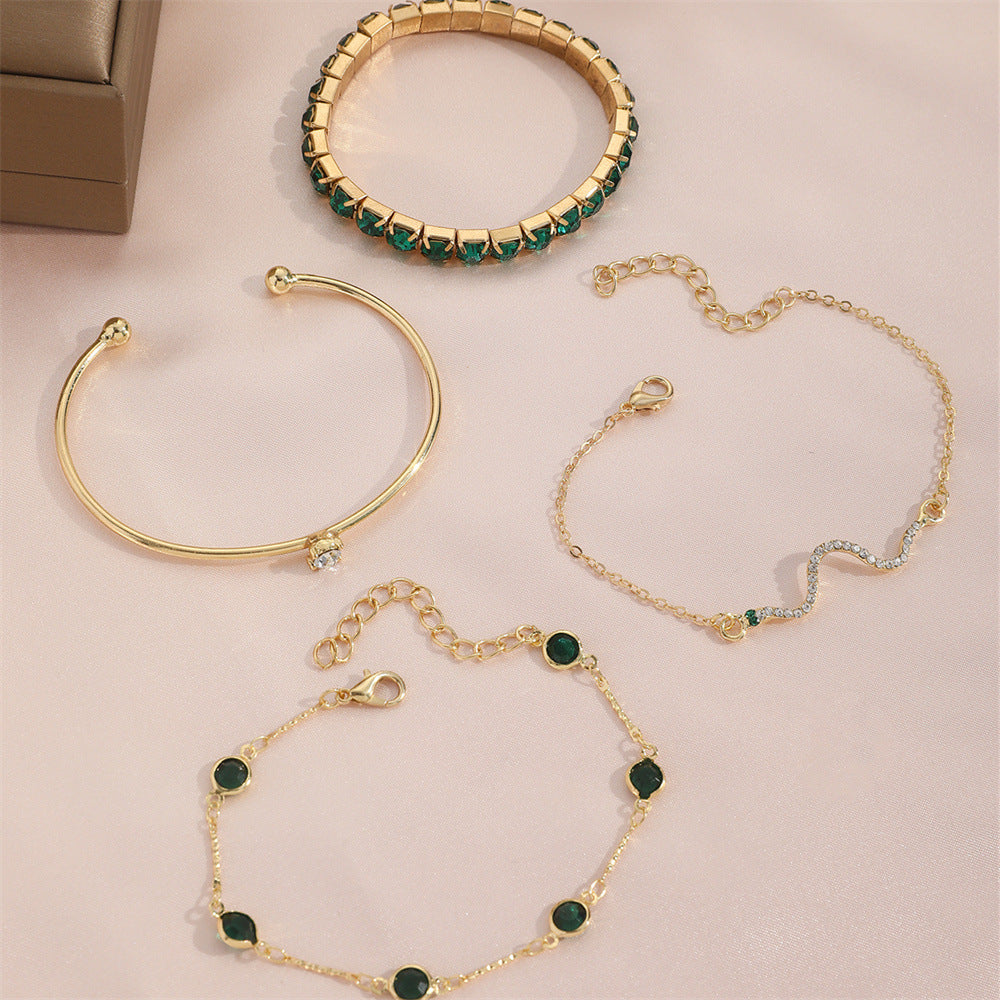 Gold-tone bracelet set with green stone bangles and linked chain bracelets, flat lay