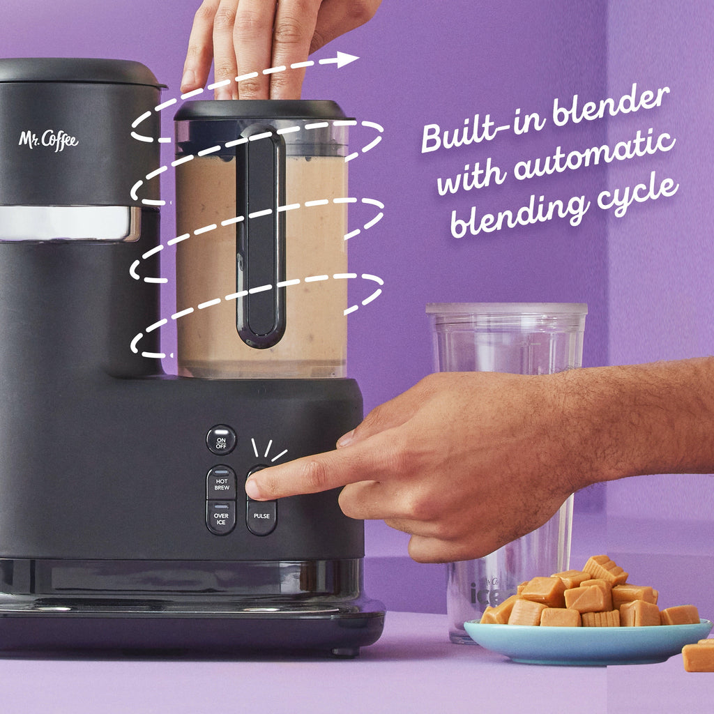 Black coffee maker close-up with blender jar and control buttons as a hand points