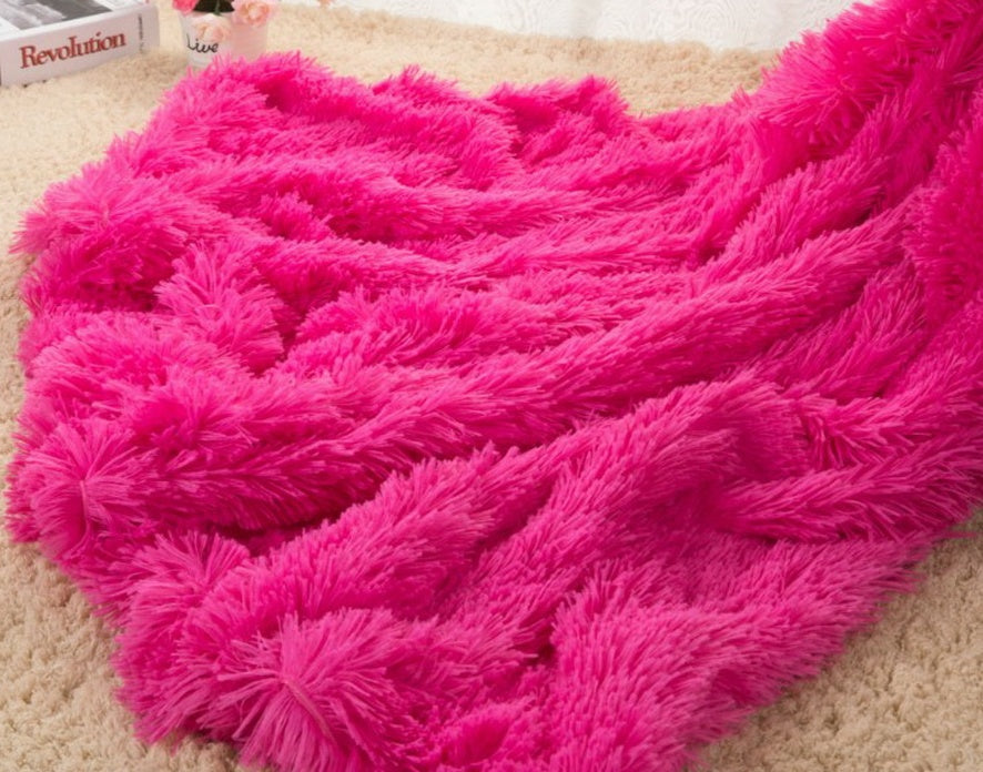 Plush throw blanket in bright pink with thick shaggy pile texture