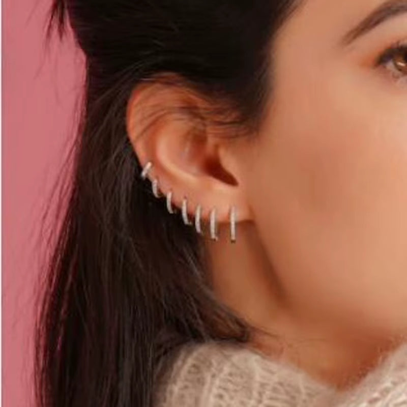 Silver crystal huggie hoop earrings with small prong-set stones along the hoop