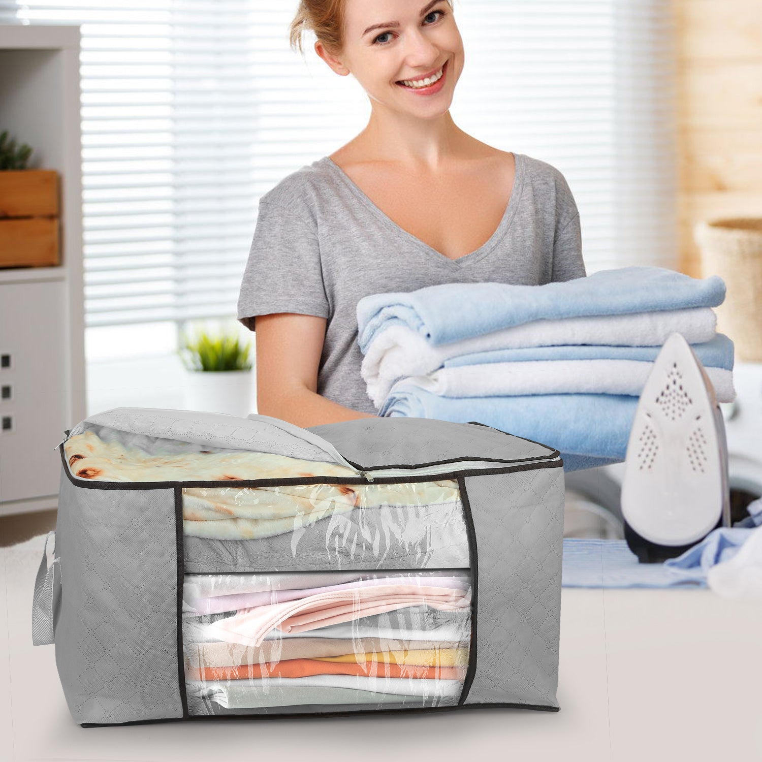 Grey set of 2 fabric clothes storage bags with clear window, being filled with folded linens