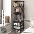 Black corner coat rack with hanging hooks holding coat, hat, and bags on storage shelves
