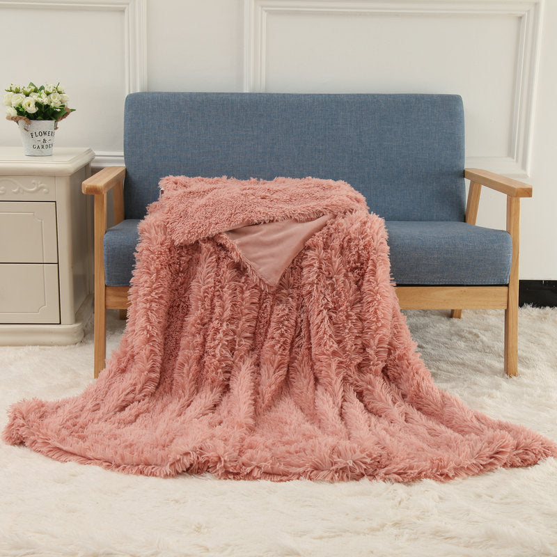 Plush throw blanket in dusty rose pink with thick shaggy pile texture