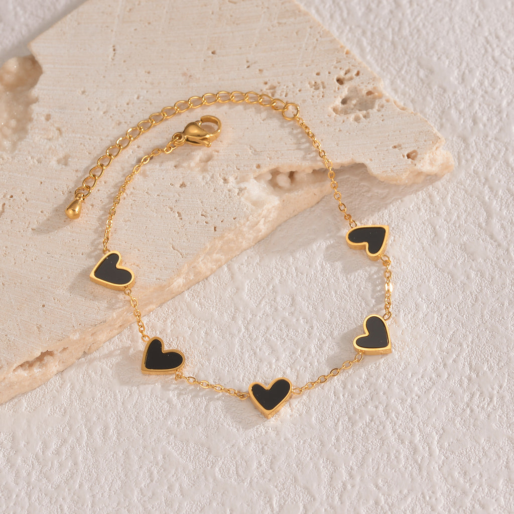 Gold-tone heart charm bracelet with black enamel heart links and chain clasp