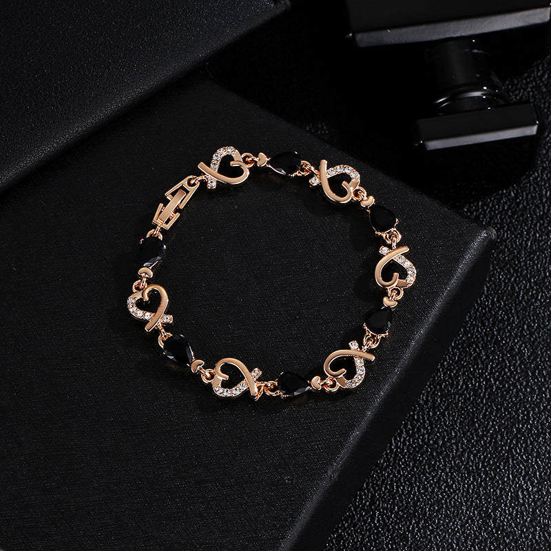 Rose gold heart bracelet with dark teardrop stones and clear rhinestone heart links.