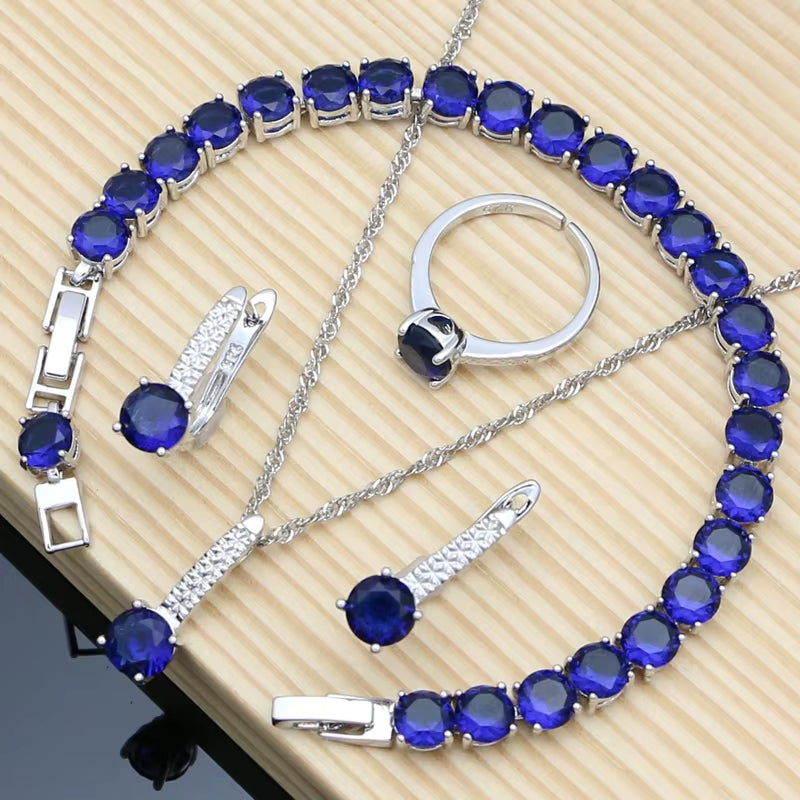 Sterling silver jewelry set with round blue gemstones: bracelet, necklace, ring, and earrings