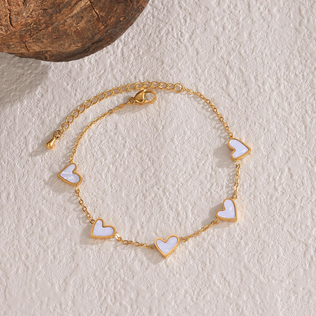 Gold-tone heart charm bracelet with white enamel heart links and chain clasp