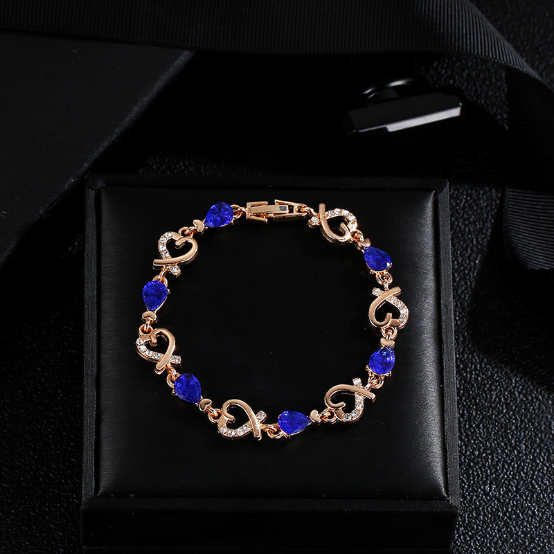 Rose gold heart bracelet with blue teardrop stones and clear rhinestone heart links.