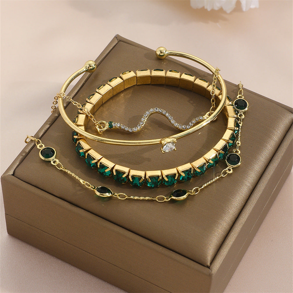 Gold-tone bracelet set with green stone cuffs and snake chain bracelets on display box