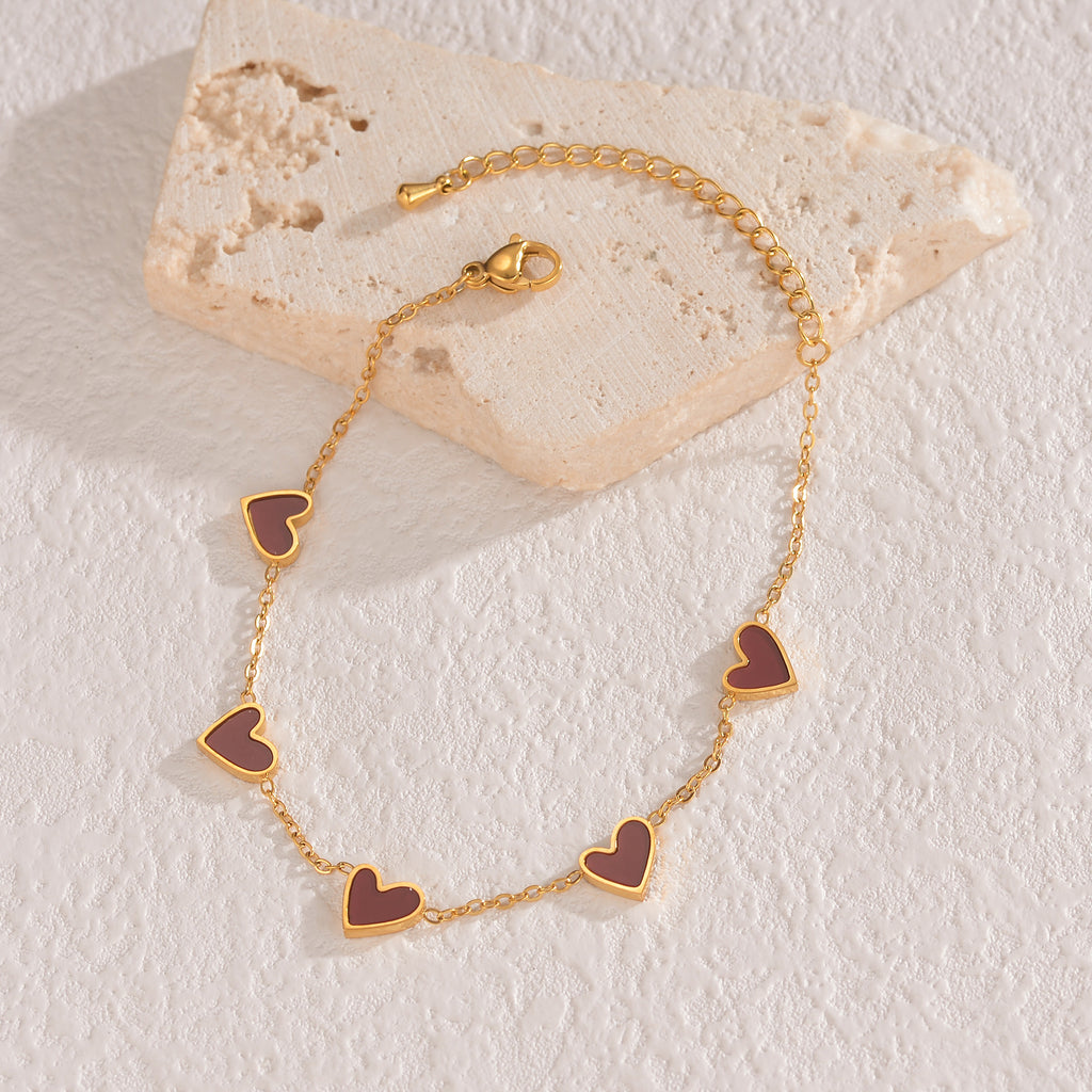 Gold-tone heart charm bracelet with mauve/pink enamel heart links and clasp