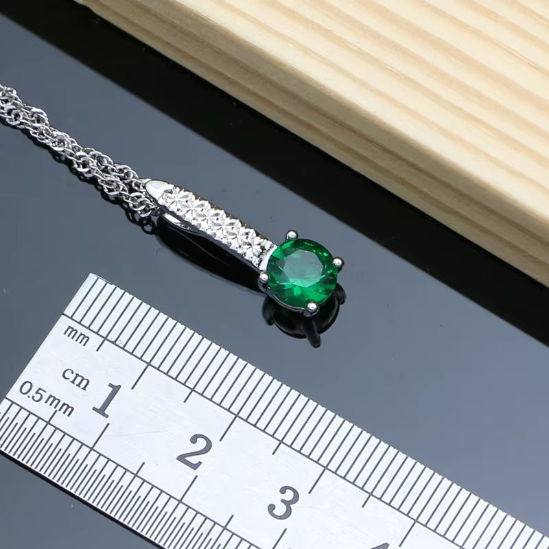 Silver necklace pendant with green oval gemstone and clear pavé stones in a bar setting