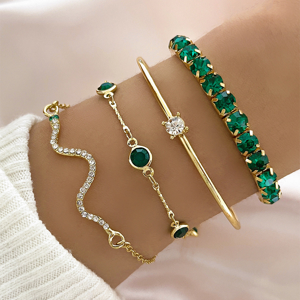 Gold-tone snake chain stretch bracelet set with green and clear stone accents on wrist