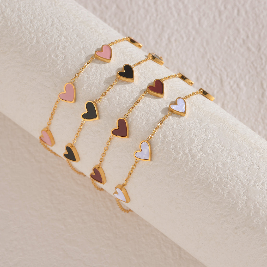 Gold-tone dripping heart bracelet with pink, black, and white heart charms